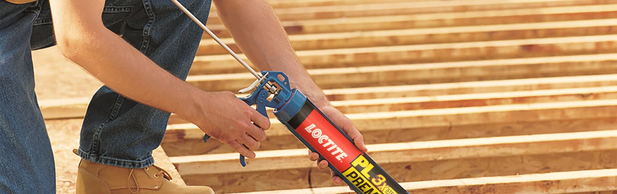 Contractor applying Loctite construction adhesive over framing